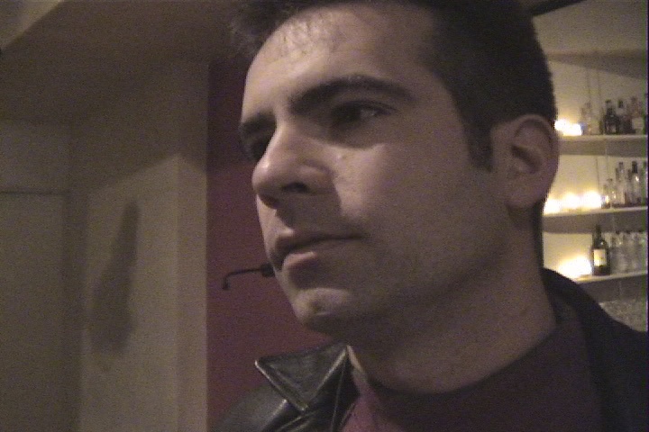 A man in a leather jacket with a tuxedo collar standing at a bar — Watershed (1999)
