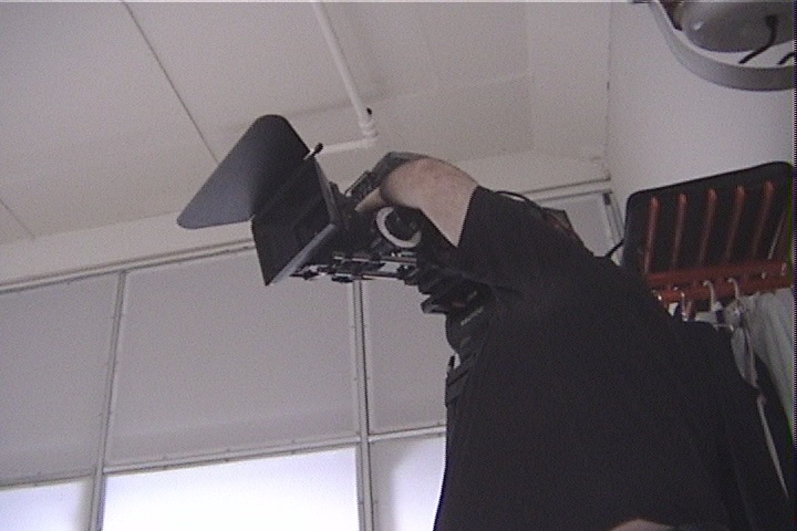 A camera operator framing a shot in a bright studio during the Watershed production (1998)