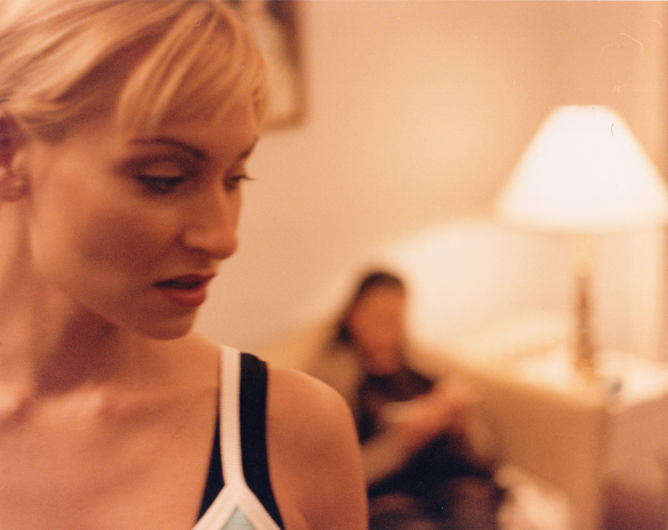 A blonde actress in a black slip top at a lamplit bedroom party — When (1999)